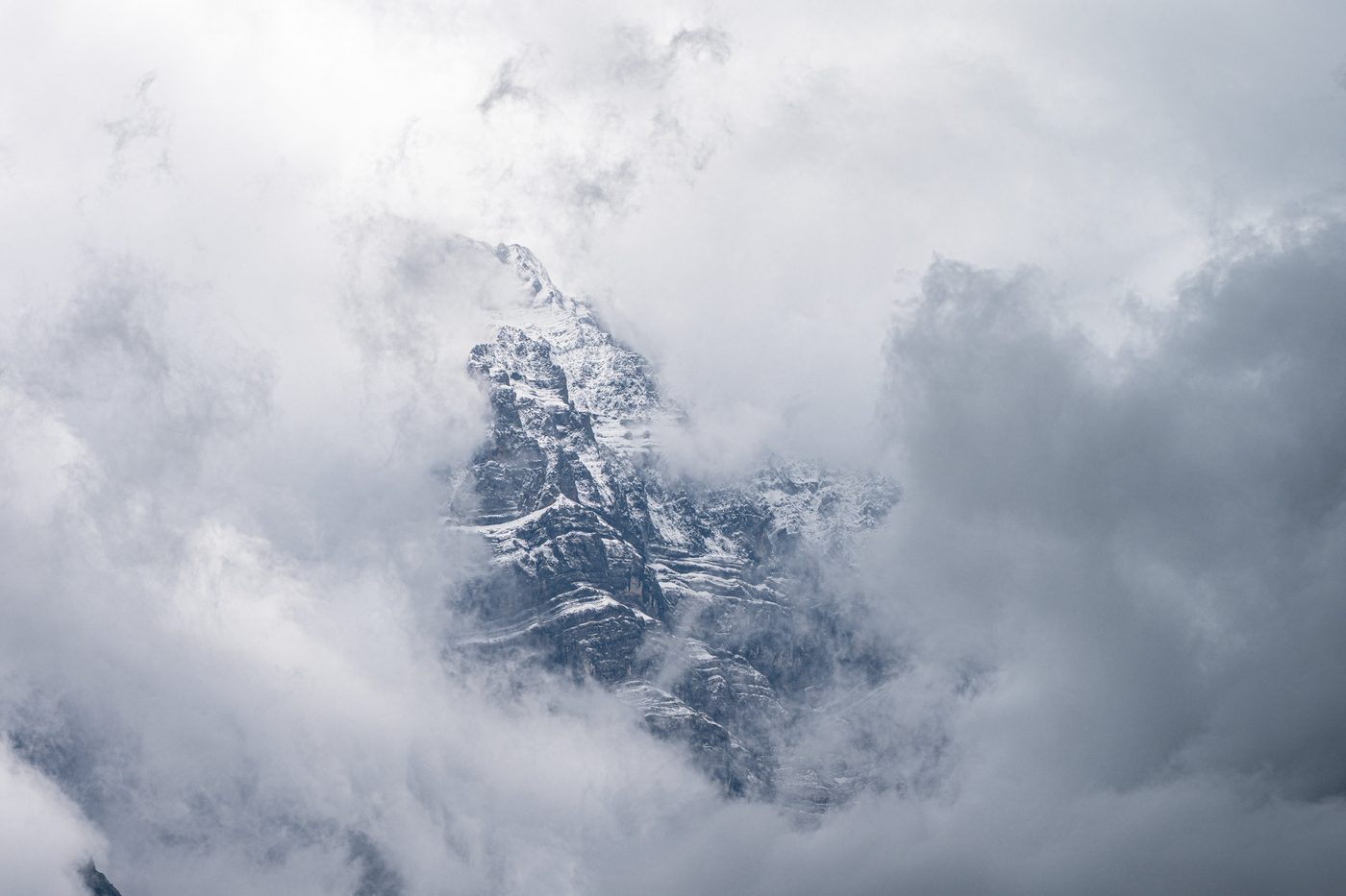 A snow-dusted rock peak half hidden in cloud