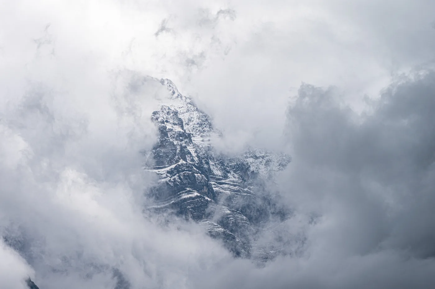 A snow-dusted rock peak half hidden in cloud