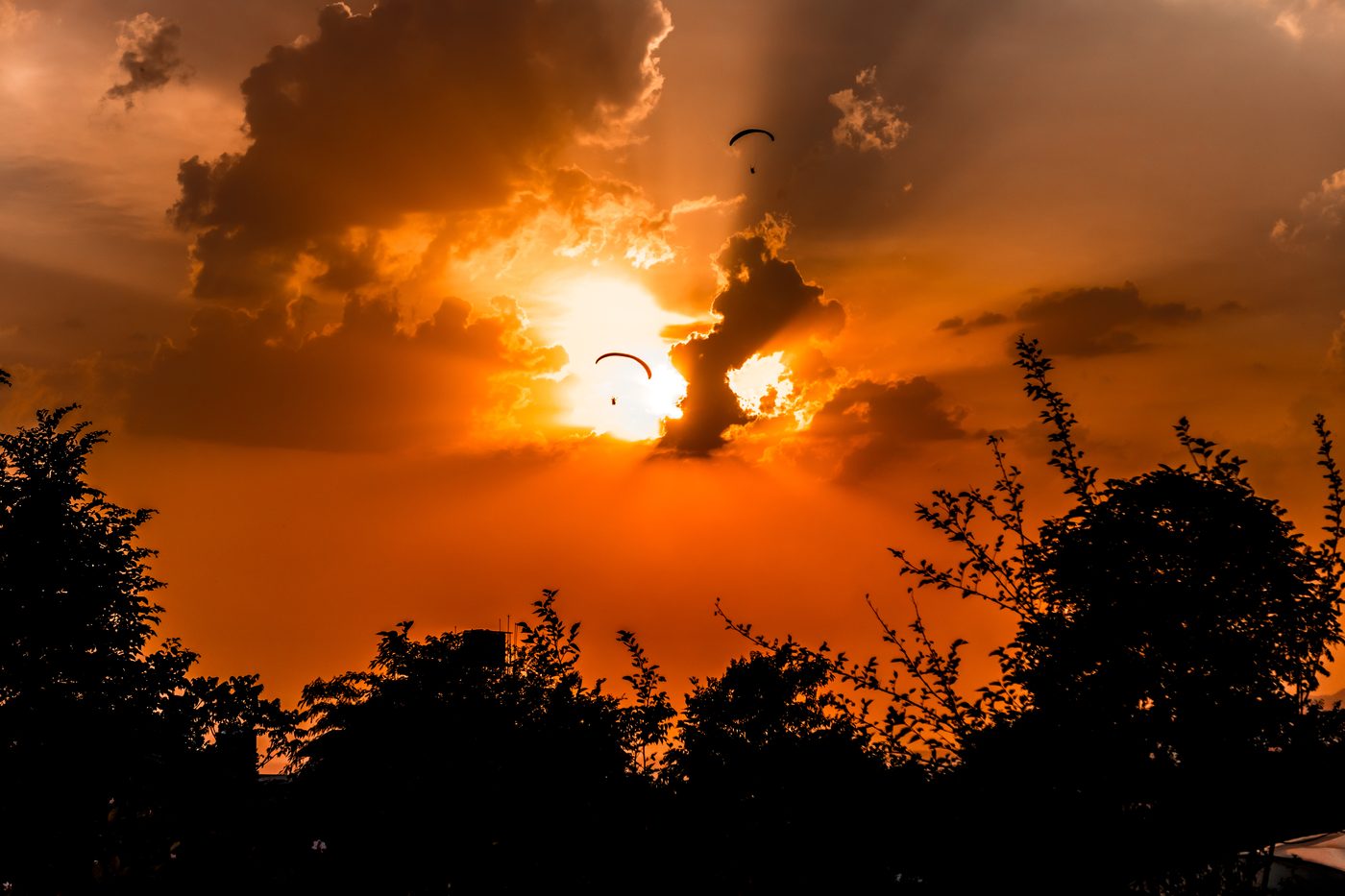 Two paragliders silhouetted against the sunset