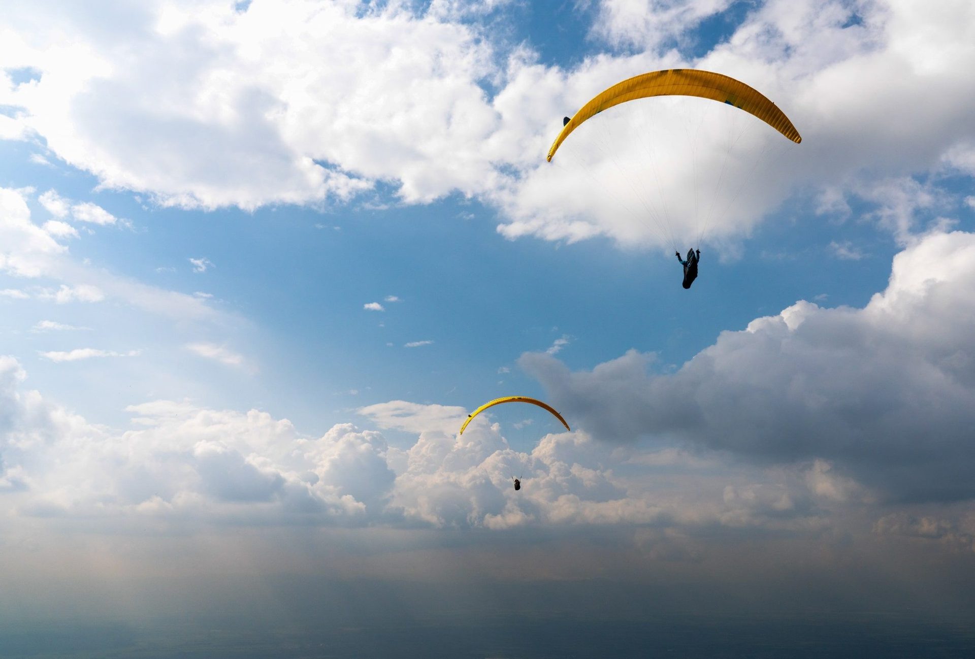 Two paragliders soaring above the clouds