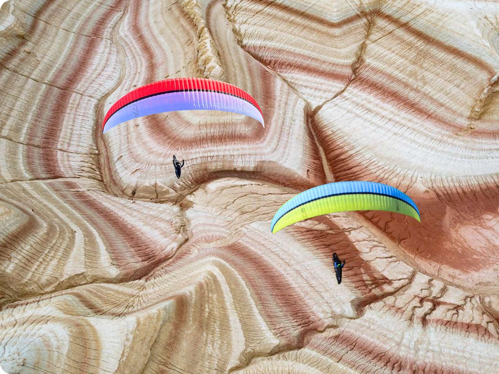 Paragliders over striped canyon terrain in Kazakhstan